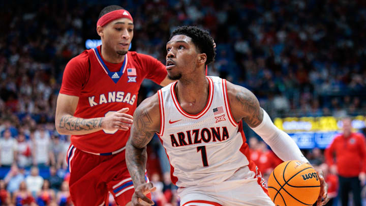 Mar 8, 2025; Lawrence, Kansas, USA; Arizona Wildcats guard Caleb Love (1) drives to the basket around Kansas Jayhawks guard Dajuan Harris Jr. (3) during the first half at Allen Fieldhouse. Mandatory Credit: William Purnell-Imagn Images