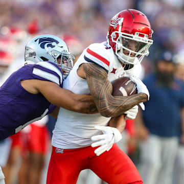 Sep 13, 2024; Manhattan, Kansas, USA; Arizona Wildcats wide receiver Tetairoa McMillan (4) is tackled by Kansas State Wildcats cornerback Keenan Garber (1) during the first quarter at Bill Snyder Family Football Stadium. 