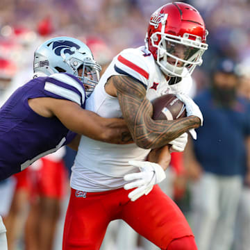 Sep 13, 2024; Manhattan, Kansas, USA; Arizona Wildcats wide receiver Tetairoa McMillan (4) is tackled by Kansas State Wildcats cornerback Keenan Garber (1) during the first quarter at Bill Snyder Family Football Stadium.