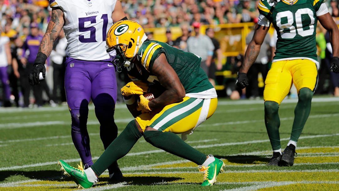 Green Bay Packers wide receiver Dontayvion Wicks (13) scores a touchdwon against Minnesota Vikings linebacker Blake Cashman (51) in the fourth quarter during their football game Sunday, September 29, 2024, at Lambeau Field in Green Bay, Wisconsin.