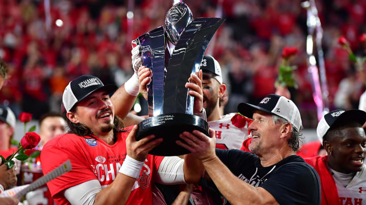 Utah Utes head coach Kyle Whittingham and quarterback Cameron Rising (7) lift the PAC-12 Football Championship trophy