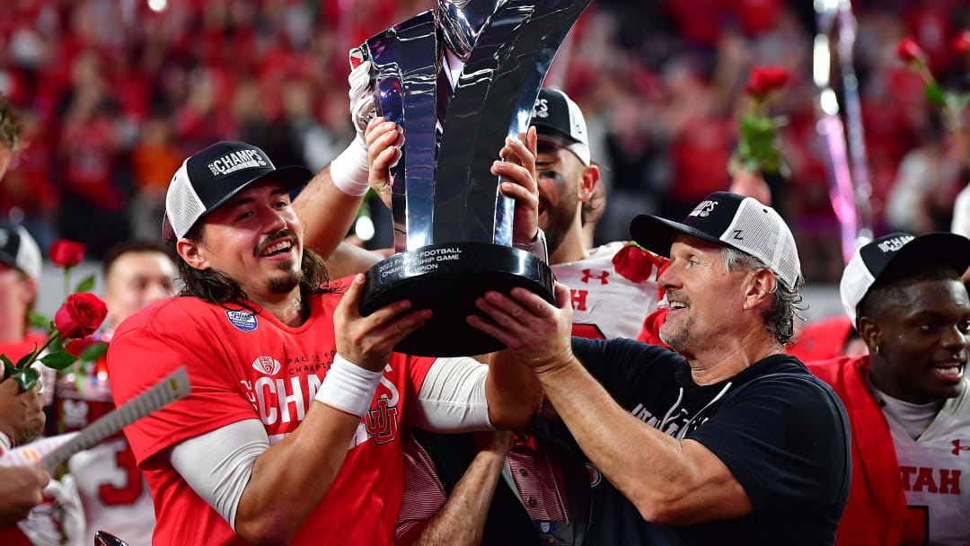 Dec 2, 2022; Las Vegas, NV, USA; Utah Utes head coach Kyle Whittingham and quarterback Cameron Rising (7) lift the PAC-12 Football Championship trophy following the victory against the Southern California Trojans at Allegiant Stadium. Mandatory Credit: Gary A. Vasquez-USA TODAY Sports