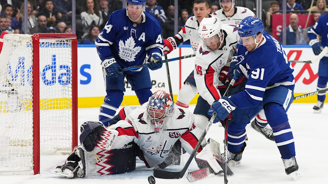 Dec 6, 2024; Toronto, Ontario, CAN; Toronto Maple Leafs center John Tavares (91) battles for the puck with Washington Capitals right winger Taylor Raddysh (16) in front of goaltender Charlie Lindgren (79) during the third period at Scotiabank Arena. Mandatory Credit: Nick Turchiaro-Imagn Images