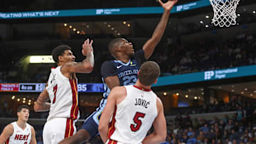 Oct 24, 2025; Memphis, Tennessee, USA; Miami Heat forward Andrew Wiggins (22) drives to the basket between Memphis Grizzlies guard Ja Morant (12) and forward/center Jaren Jackson Jr. (8) during the second quarter at FedExForum. Mandatory Credit: Petre Thomas-Imagn Images