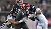 Nov 9, 2024; Pullman, Washington, USA; Washington State Cougars running back Wayshawn Parker (21) is tackled by Utah State Aggies safety Jordan Vincent (24) and cornerback D.J. Graham II (4) in the first half at Gesa Field at Martin Stadium. Mandatory Credit: James Snook-Imagn Images