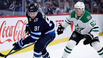Mar 14, 2025; Winnipeg, Manitoba, CAN;  Winnipeg Jets forward Cole Perfetti (91) and Dallas Stars forward Wyatt Johnston (53) skate for the puck during the second period at Canada Life Centre. Mandatory Credit: Terrence Lee-Imagn Images