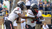 Oct 11, 2025; South Bend, Indiana, USA; NC State Wolfpack quarterback CJ Bailey (11) hands off to NC State Wolfpack running back Hollywood Smothers (3) during the first half at Notre Dame Stadium. Mandatory Credit: Michael Caterina-Imagn Images