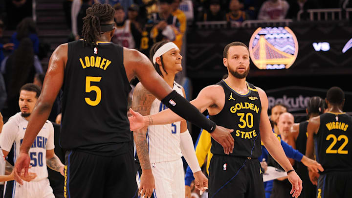Golden State Warriors guard Stephen Curry (30) high-fives forward Kevon Looney (5) as a timeout is called during the fourth quarter against the Orlando Magic at Chase Center.