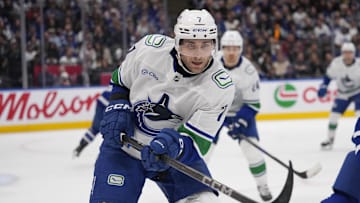 Jan 11, 2025; Toronto, Ontario, CAN; Vancouver Canucks defenseman Carson Soucy (7) goes after a loose puck against the Toronto Maple Leafs during the third period at Scotiabank Arena. Mandatory Credit: John E. Sokolowski-Imagn Images