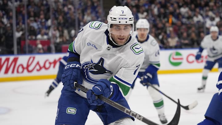 Jan 11, 2025; Toronto, Ontario, CAN; Vancouver Canucks defenseman Carson Soucy (7) goes after a loose puck against the Toronto Maple Leafs during the third period at Scotiabank Arena. Mandatory Credit: John E. Sokolowski-Imagn Images