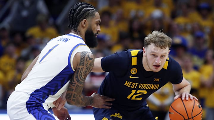 Nov 15, 2024; Pittsburgh, Pennsylvania, USA;  West Virginia Mountaineers guard Tucker DeVries (12) brings the ball up court against pressure from Pittsburgh Panthers guard Damian Dunn (1) during the first half at the Petersen Events Center. Mandatory Credit: Charles LeClaire-Imagn Images