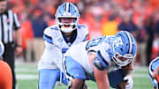 Oct 31, 2025; Syracuse, New York, USA; North Carolina Tar Heels quarterback Gio Lopez (7) with center Austin Blaske (58) at the line of scrimmage in the third quarter against the Syracuse Orange at the JMA Wireless Dome. Mandatory Credit: Mark Konezny-Imagn Images
