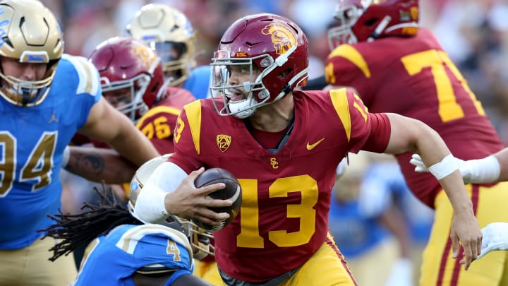 Nov 18, 2023; Los Angeles, California, USA; USC Trojans quarterback Caleb Williams (13) scrambles against UCLA Bruins defensive lineman Carl Jones Jr. (4) during the second quarter at United Airlines Field at Los Angeles Memorial Coliseum.