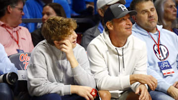 Feb 15, 2025; Oxford, Mississippi, USA; Mississippi Rebels head football coach Lane Kiffin (right) sits court-side with his son Knox Kiffin (left) during the second half between the Mississippi State Bulldogs and the Mississippi Rebels at The Sandy and John Black Pavilion at Ole Miss. Mandatory Credit: Petre Thomas-Imagn Images