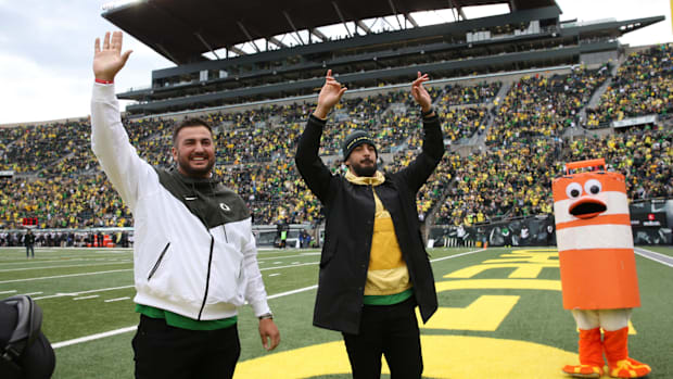 Former Oregon football players Hroniss Grasu, left, and Marcus Mariota wave to the crowd during the game against Colorado Sat