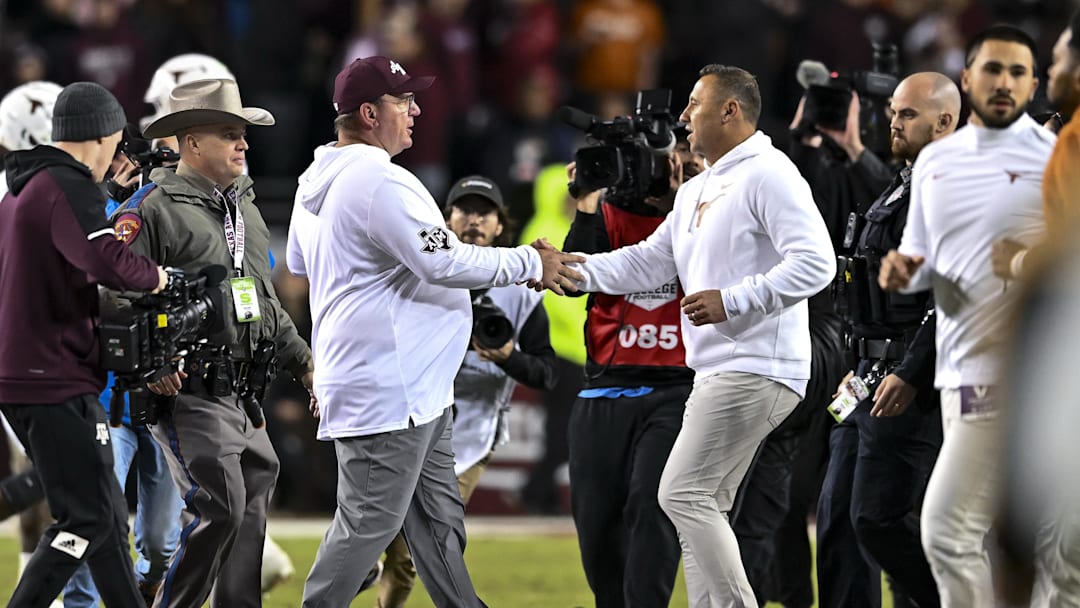 Nov 30, 2024; College Station, Texas, USA; Texas A&M Aggies head coach Mike Elko, left, shakes hands with Texas Longhorns head coach Steve Sarkisian after the game. The Longhorns defeated the Aggies 17-7. at Kyle Field. Mandatory Credit: Maria Lysaker-Imagn Images 