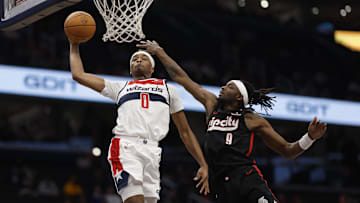 Feb 26, 2025; Washington, District of Columbia, USA; Washington Wizards guard Bilal Coulibaly (0) dunks the ball as Portland Trail Blazers forward Jerami Grant (9) defends in the second half at Capital One Arena. Mandatory Credit: Geoff Burke-Imagn Images