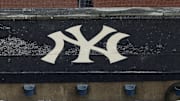 Aug 17, 2020; Bronx, New York, USA; A general view of rain falling on the  New York Yankees logo on the first base dugout roof during a rain delay in the game between the New York Yankees and the Boston Red Sox. Mandatory Credit: Vincent Carchietta-Imagn Images