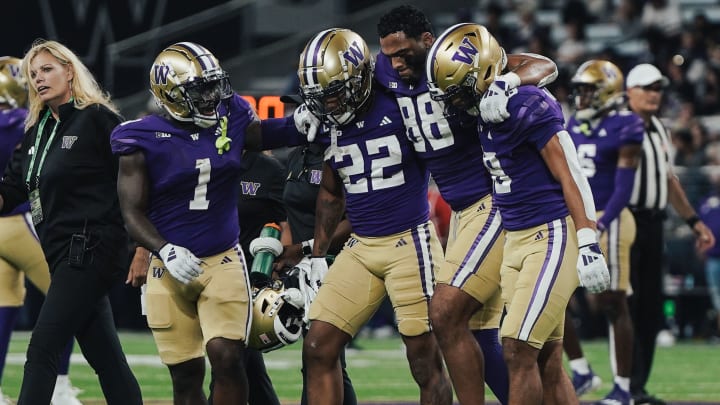 Tight end Quentin Moore is helped off the field by his UW teammates. 