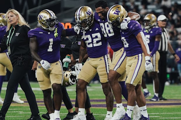 Tight end Quentin Moore is helped off the field by his UW teammates. 