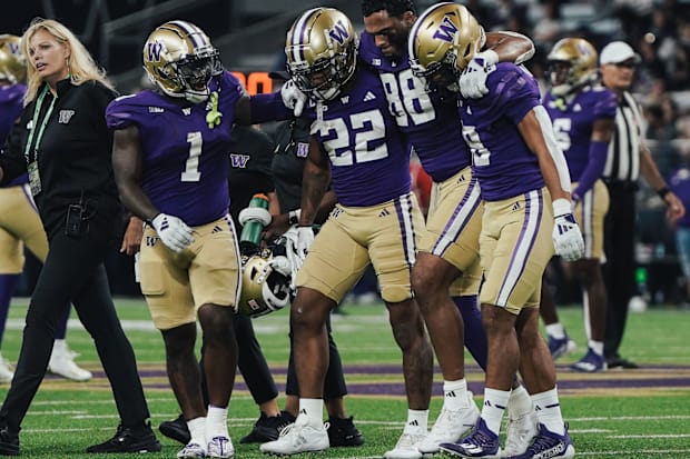 Tight end Quentin Moore is helped off the field by his UW teammates. 