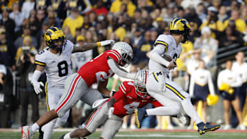 Nov 26, 2022; Columbus, Ohio, USA;  Michigan Wolverines quarterback J.J. McCarthy (9) rushes at Ohio State Buckeyes defensive end Omari Abor (23) and cornerback JK Johnson (4) at Ohio Stadium. Mandatory Credit: Rick Osentoski-Imagn Images