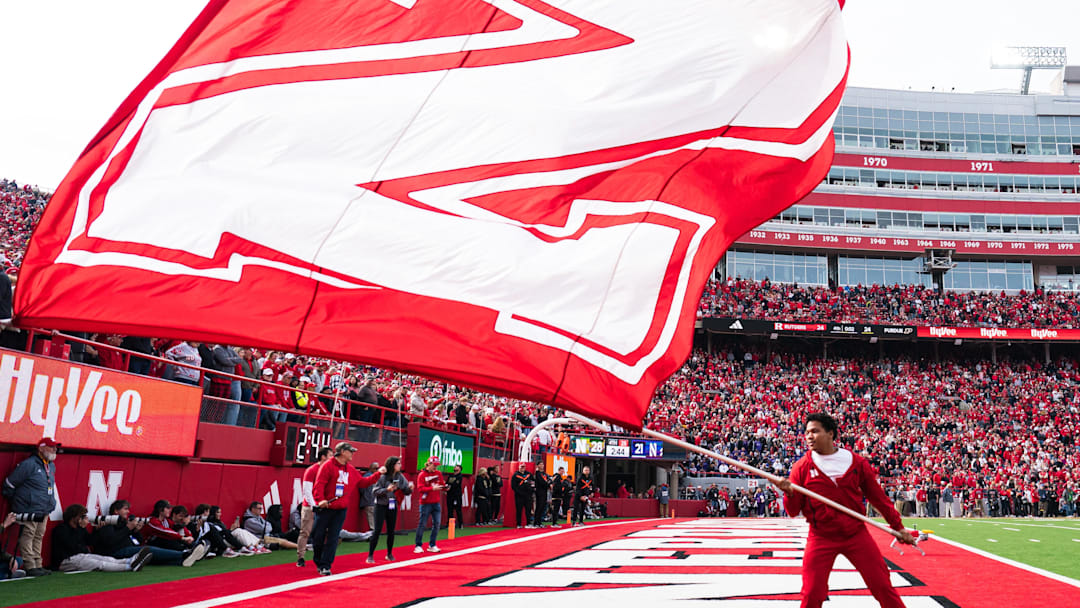 A Nebraska Cornhuskers cheerleader waves a school flag after a touchdown at Memorial Stadium. Dylan Widger-Imagn Images