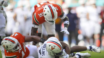Oct 28, 2023; Miami Gardens, Florida, USA; Virginia Cavaliers running back Mike Hollins (7) runs with the football against Miami Hurricanes defensive lineman Rueben Bain Jr. (44) and linebacker Wesley Bissainthe (31) during the first quarter at Hard Rock Stadium. Mandatory Credit: Sam Navarro-USA TODAY Sports
