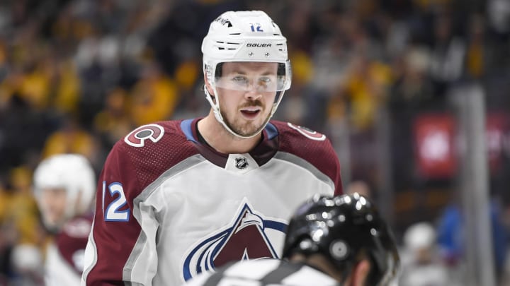 Nov 20, 2023; Nashville, Tennessee, USA; Colorado Avalanche center Ryan Johansen (12) mouths to linesman Bevan Mills (53) after not dropping the puck against the Nashville Predators during the second period at Bridgestone Arena. Mandatory Credit: Steve Roberts-USA TODAY Sports