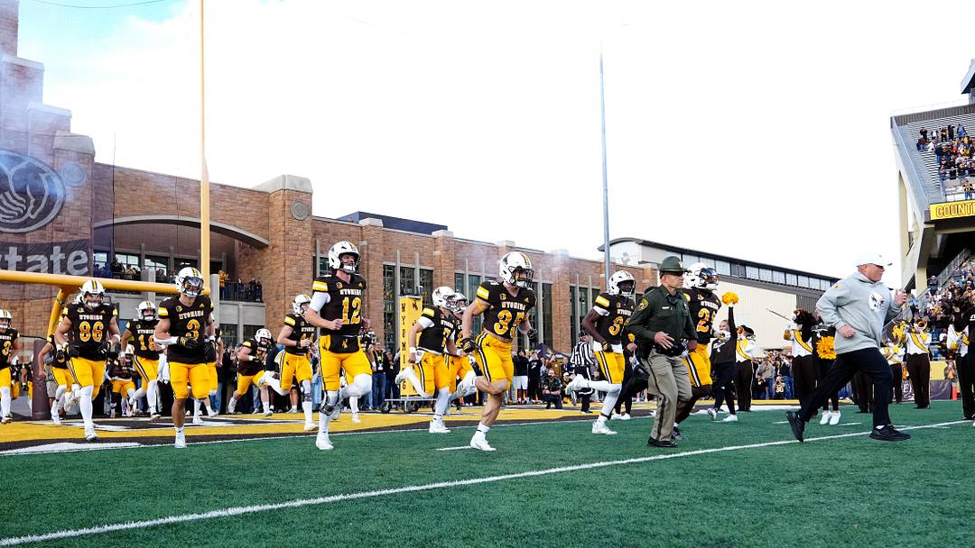 Sep 13, 2025; Laramie, Wyoming, USA; Wyoming Cowboys head coach Jay Sawvel (right) leads the team out before the game against the Utah Utes at Jonah Field at War Memorial Stadium. Mandatory Credit: Ron Chenoy-Imagn Images