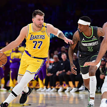 Apr 30, 2025; Los Angeles, California, USA; Los Angeles Lakers guard Luka Doncic (77) moves the ball against Minnesota Timberwolves forward Jaden McDaniels (3) and center Rudy Gobert (27) during the first half in game five of first round for the 2025 NBA Playoffs at Crypto.com Arena. Mandatory Credit: Gary A. Vasquez-Imagn Images