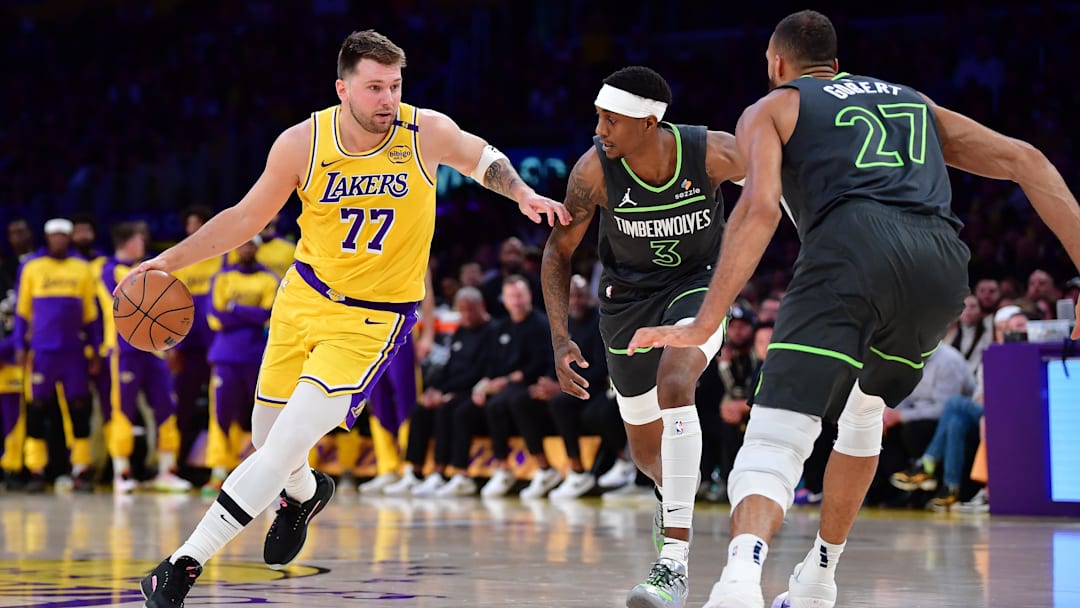 Apr 30, 2025; Los Angeles, California, USA; Los Angeles Lakers guard Luka Doncic (77) moves the ball against Minnesota Timberwolves forward Jaden McDaniels (3) and center Rudy Gobert (27) during the first half in game five of first round for the 2025 NBA Playoffs at Crypto.com Arena. Mandatory Credit: Gary A. Vasquez-Imagn Images