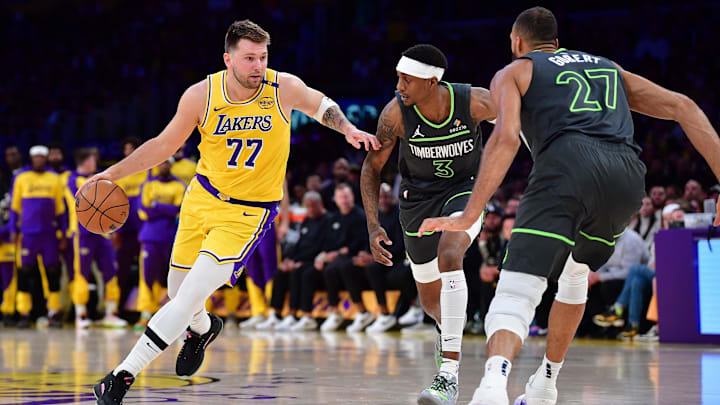 Apr 30, 2025; Los Angeles, California, USA; Los Angeles Lakers guard Luka Doncic (77) moves the ball against Minnesota Timberwolves forward Jaden McDaniels (3) and center Rudy Gobert (27) during the first half in game five of first round for the 2025 NBA Playoffs at Crypto.com Arena. Mandatory Credit: Gary A. Vasquez-Imagn Images