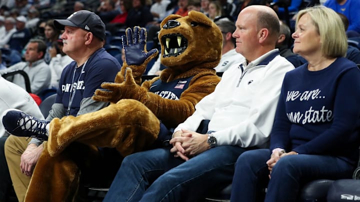 Penn State Nittany Lion mascot sitting with fans.