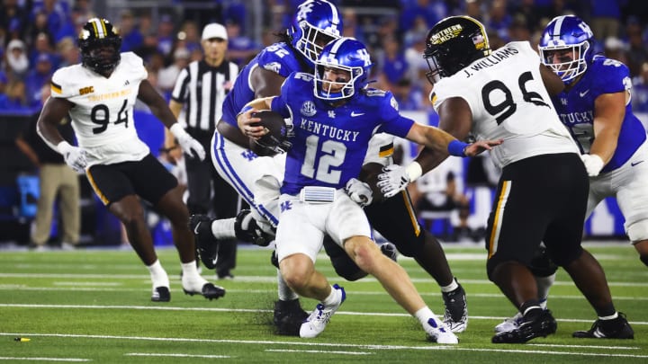 Aug 31, 2024; Lexington, Kentucky, USA; Kentucky Wildcats quarterback Brock Vandagriff (12) slides between Southern Miss Golden Eagles defensive lineman Jalen Williams (96) during the second quarter at Kroger Field. Mandatory Credit: Carter Skaggs-USA TODAY Sports