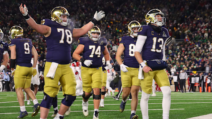 Riley Leonard #13 of the Notre Dame Fighting Irish celebrates with teammates after running the ball for a touchdown during the fourth quarter against the Indiana Hoosiers in the Playoff First Round game at Notre Dame Stadium on December 20, 2024 in South Bend, Indiana. Leonard set the record for the most rushing touchdowns by a Notre Dame quarterback with 15, passing Brandon Wimbush’s 2017 mark. Notre Dame defeated Indiana 27-17.