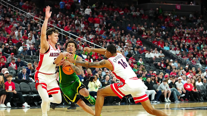Mar 15, 2024; Las Vegas, NV, USA; Oregon Ducks guard Jadrian Tracey (22) dribbles between Arizona Wildcats guard Pelle Larsson (3) and Arizona Wildcats forward Keshad Johnson (16) during the first half at T-Mobile Arena. Mandatory Credit: Stephen R. Sylvanie-Imagn Images