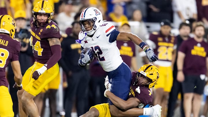 Nov 28, 2025; Tempe, Arizona, USA; Arizona Wildcats wide receiver Tre Spivey (12) is tackled by Arizona State Sun Devils defensive back Montana Warren (7) during the 99th Territorial Cup at Mountain America Stadium. Mandatory Credit: Mark J. Rebilas-Imagn Images