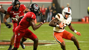 Nov 4, 2023; Raleigh, North Carolina, USA; Miami Hurricanes running back Mark Fletcher Jr. (22) runs as North Carolina State Wolfpack cornerback Shyheim Battle (7) defends during the first half at Carter-Finley Stadium. Mandatory Credit: Rob Kinnan-Imagn Images
