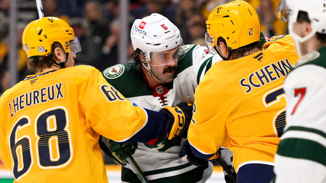 Jan 18, 2025; Nashville, Tennessee, USA;  Minnesota Wild defenseman Jake Middleton (5) takes on Nashville Predators defenseman Luke Schenn (2) and left wing Zachary L'Heureux (68) during the second period at Bridgestone Arena. Mandatory Credit: Steve Roberts-Imagn Images