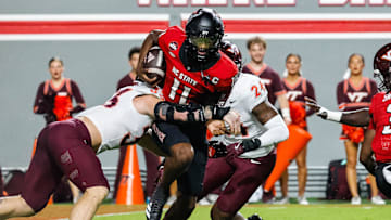 Sep 27, 2025; Raleigh, North Carolina, USA;  North Carolina State Wolfpack quarterback CJ Bailey (11) attempts to run the ball but is tackled by Virginia Tech Hokies defensive lineman Ben Bell (33) and linebacker Jaden Keller (24)  during the first half of the game at Carter-Finley Stadium. Mandatory Credit: Jaylynn Nash-Imagn Images