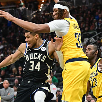 Apr 27, 2025; Milwaukee, Wisconsin, USA; Milwaukee Bucks forward Giannis Antetokounmpo (34) reaches for a rebound against Indiana Pacers center Myles Turner (33) and guard Andrew Nembhard (2) in the third quarter during game four of first round for the 2024 NBA Playoffs at Fiserv Forum. Mandatory Credit: Benny Sieu-Imagn Images