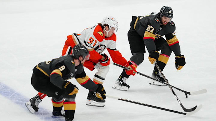 Dec 23, 2024; Las Vegas, Nevada, USA; Anaheim Ducks center Leo Carlsson (91) skates between Vegas Golden Knights defenseman Shea Theodore (27) and Vegas Golden Knights center Jack Eichel (9) during the second period at T-Mobile Arena. Mandatory Credit: Stephen R. Sylvanie-Imagn Images