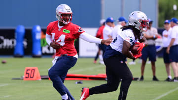 Jun 10, 2024; Foxborough, MA, USA;  New England Patriots quarterback Jacoby Brissett (14) hands the ball to running back Rhamondre Stevenson (38) at minicamp at Gillette Stadium. Mandatory Credit: Eric Canha-USA TODAY Sports