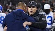 Nov 22, 2025; Cincinnati, Ohio, USA; Cincinnati Bearcats head coach Scott Satterfield, right, hugs BYU Cougars head coach Kalani Sitake after their game at Nippert Stadium. Mandatory Credit: Aaron Doster-Imagn Images