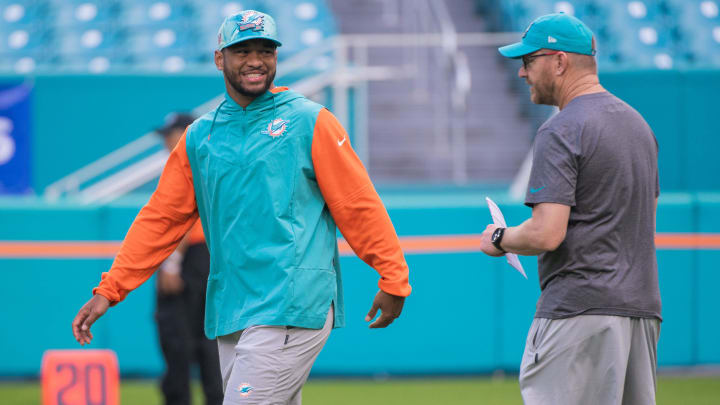 Miami Dolphins quarterback Tua Tagovailoa smiles while speaking with Dolphins quarterback coach Darrell Bevell before the start of the game against the Houston Texans at Hard Rock Stadium in 2022.