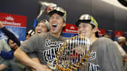 Oct 31, 2025; Toronto, Ontario, CAN; Los Angeles Dodgers two-way player Shohei Ohtani (17) and pitcher Yoshinobu Yamamoto (18) and pitcher Roki Sasaki (11) celebrate with the Commissioner's Trophy in the clubhouse after defeating the Toronto Blue Jays in the 2025 MLB World Series at Rogers Centre. Mandatory Credit: John E. Sokolowski-Imagn Images