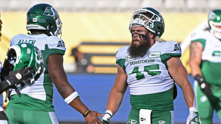 Jun 16, 2024; Hamilton, Ontario, CAN; Saskatchewan Rough Riders wide receiver Justin Bane Jr (15) and Saskatchewan Rough Riders linebacker AJ Allen (32) during warmups against the Hamilton Tiger Cats at Tim Hortons Field. Mandatory Credit: Gerry Angus-USA TODAY Sports