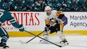 Jan 27, 2025; San Jose, California, USA;  Pittsburgh Penguins defenseman Erik Karlsson (65) controls the puck against San Jose Sharks defenseman Mario Ferraro (38) in the third period at SAP Center at San Jose. Mandatory Credit: David Gonzales-Imagn Images