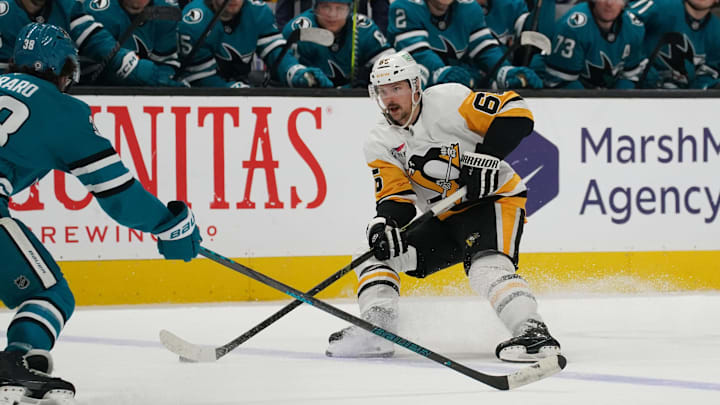 Jan 27, 2025; San Jose, California, USA;  Pittsburgh Penguins defenseman Erik Karlsson (65) controls the puck against San Jose Sharks defenseman Mario Ferraro (38) in the third period at SAP Center at San Jose. Mandatory Credit: David Gonzales-Imagn Images